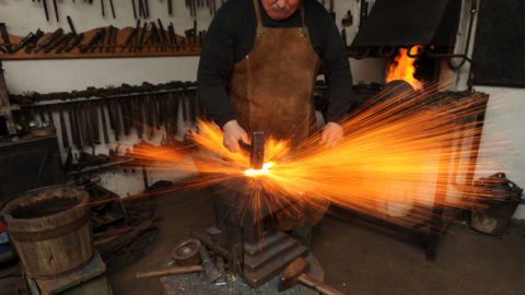 a blacksmith working on a piece of metal with sparks flying